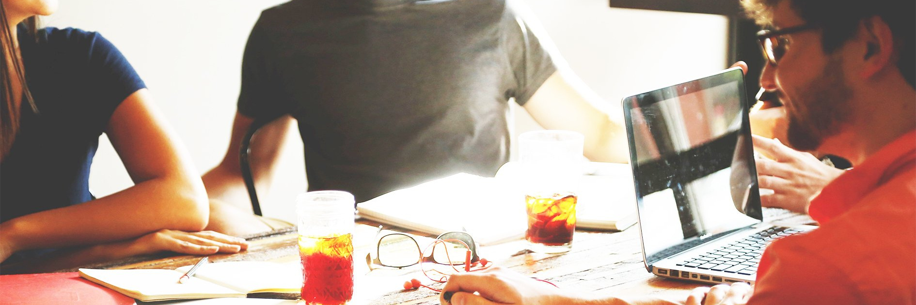 Three persons sit at a table with working materials.