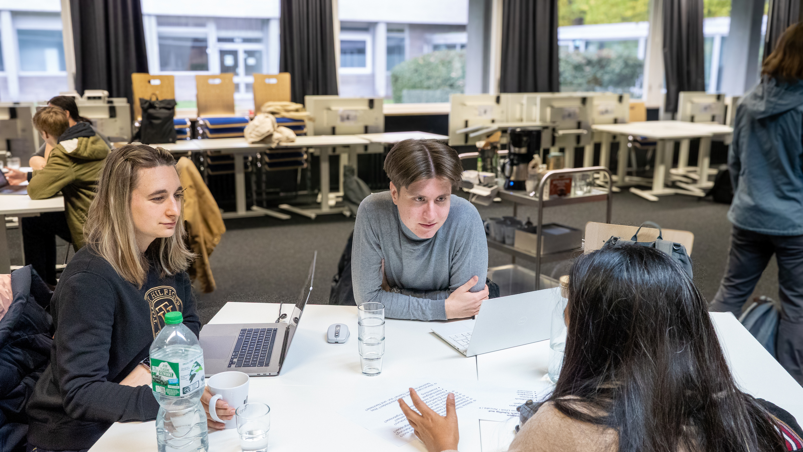 Die Teilnehmenden arbeiten in Gruppenarbeiten an Tischen und diskutieren